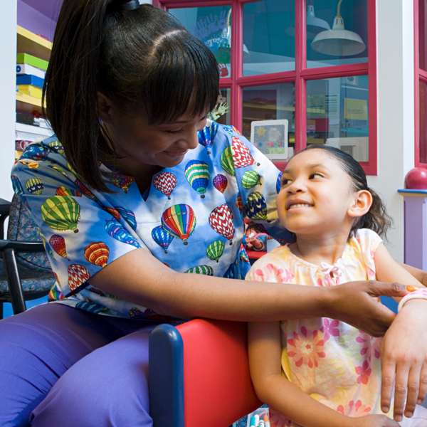 Nurse wearing custom tailored gown helping a child